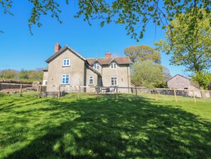 A large stone house with a fenced yard and a clear blue sky. - Beach Farmhouse (Bishops Castle)