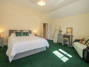 A bedroom with a bed, bedside tables, a dresser, a mirror, and a chair. - Beach Farmhouse (Bishops Castle)