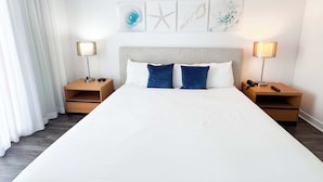 Habitació d'hotel amb un llit gran, dues taules de nit, un capçal de llit i obra d'art a la paret.