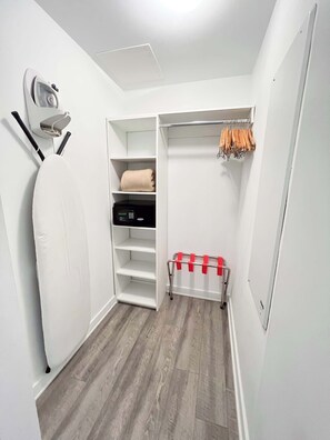 Ein begehbarer Kleiderschrank mit Regalen, einer Kleiderstange und einem Bügelbrett.