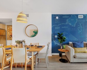 Ein modernes Wohnzimmer mit Essbereich, einer großen Wandkarte und einer Couch mit dekorativen Kissen.
