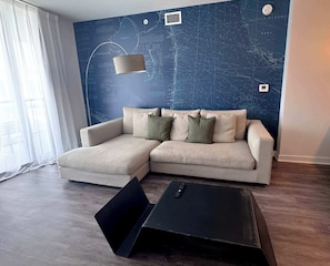 Ein modernes Wohnzimmer mit einem Ecksofa, einem schwarzen Couchtisch und einer großen Wandkarte.