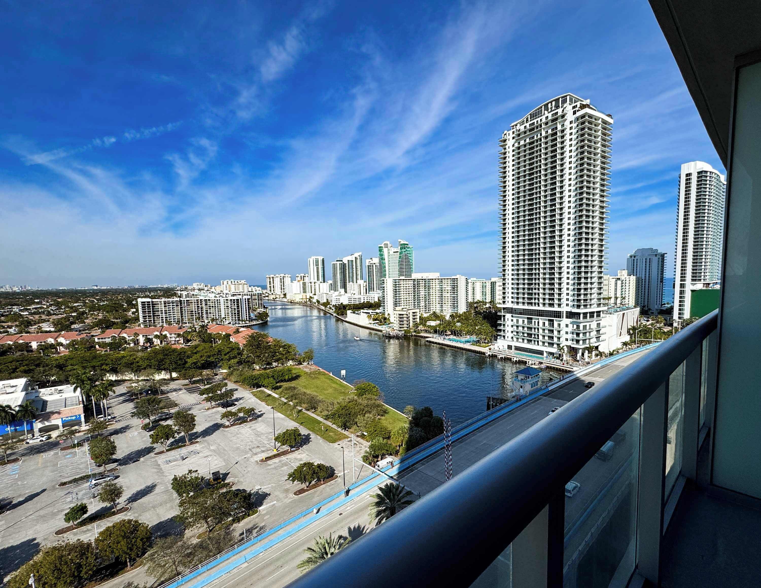 A high-rise building with a view of a river and a parking lot.