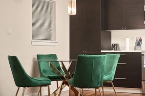 A modern kitchen with dark cabinets, a glass dining table, and green upholstered chairs. - Near Airport  & Hospital / Fast WiFi / Parking (McAllen)