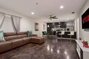 A modern living room with a sectional sofa, a dining area with chairs, a kitchen with a bar, and a ceiling fan. - Near Airport  & Hospital / Fast WiFi / Parking (McAllen)