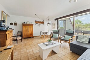 A spacious living area with a dining table, chairs, a sofa, a coffee table, and a wooden cabinet. - Westduin GV003 + G19* (De Panne)