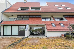 A modern two-story building with a red-tiled roof, large windows, and a covered outdoor seating area. - Westduin GV003 + G19* (De Panne)