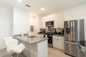 A modern kitchen with a granite countertop, stainless steel appliances, and white cabinetry.