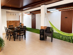 A dining area with a table and chairs, a speaker, and a hammock.