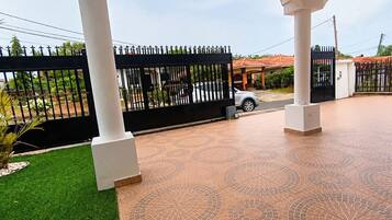 A gated entrance with a paved driveway, a white column structure, and a vehicle parked inside.