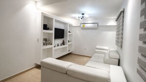 Una sala de estar moderna con un sofá blanco, unidad de entretenimiento empotrada y un televisor de pantalla plana.