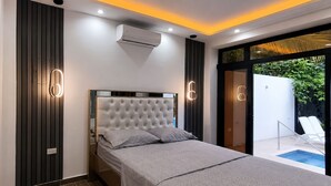 Ein modernes Schlafzimmer mit einem großen Bett, einer integrierten Klimaanlage und Blick auf einen Swimmingpool.