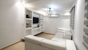 A modern living room with a white sofa, built-in entertainment unit, and a mounted TV.