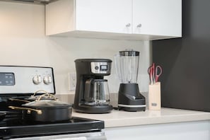 Eine Küche mit Herd, Kaffeemaschine, Mixer und Schrank.