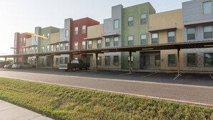 A row of multi-story buildings with a covered parking area in front. - King Size Beds/ Fast WiFi / Spacious/ Close to DHR (Edinburg)