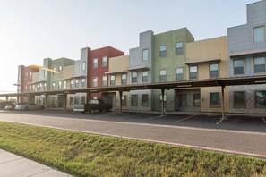 Une rangée d’immeubles à plusieurs étages, avec un espace de stationnement couvert à l’avant.