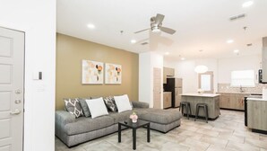 A modern living room with a grey sofa, a coffee table, and a ceiling fan. - King Size Beds/ Fast WiFi / Spacious/ Close to DHR (Edinburg)