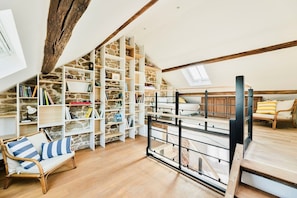 Ein Schlafzimmer im Loft-Stil mit einer Steinwand, Holzbalken, einem Etagenbett, einem großen Bücherregal und einem Fenster.