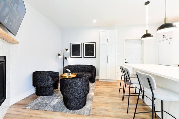 A modern living room with a sofa, coffee table, and chairs, a white cabinet, and a fireplace.