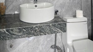 Een badkamer met een ronde spiegel, een wit wastafelmeubel en marmeren wanden.