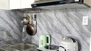 Een keuken met een marmeren aanrecht, een waterkoker, een rijstkoker en een afzuigkap.
