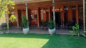 Un edificio tradicional con techo de tejas, columnas de madera y grandes macetas con plantas en primer plano.