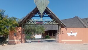 Un edificio con una estructura de techo triangular distintiva, un acceso con portón y un cartel que indica una zona de estacionamiento.