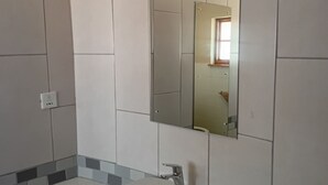 Baño con lavamanos, espejo y paredes de azulejos.