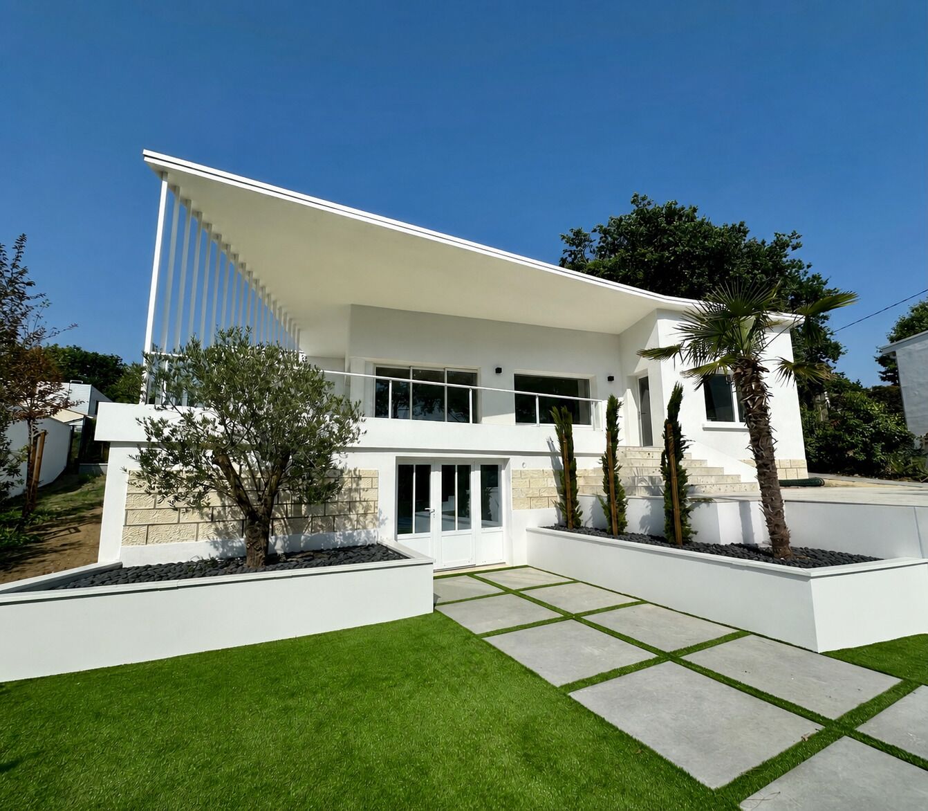 A modern two-story house with a flat roof, large windows, and a well-maintained lawn.