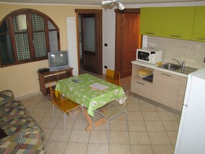 A compact kitchen with a dining table, a television, and basic appliances.