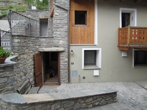 Un bâtiment en pierre doté d’un balcon en bois, d’une porte et d’une petite fenêtre.