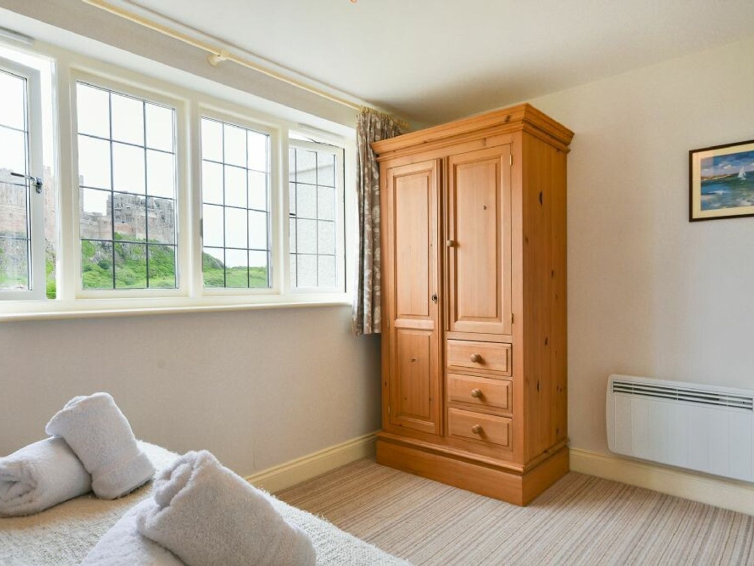 Quarto com um grande armário de madeira, radiador e janela com vista para o verde.