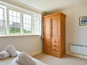 Une pièce dotée d’une grande armoire en bois, d’un radiateur et d’une fenêtre donnant sur un paysage verdoyant.