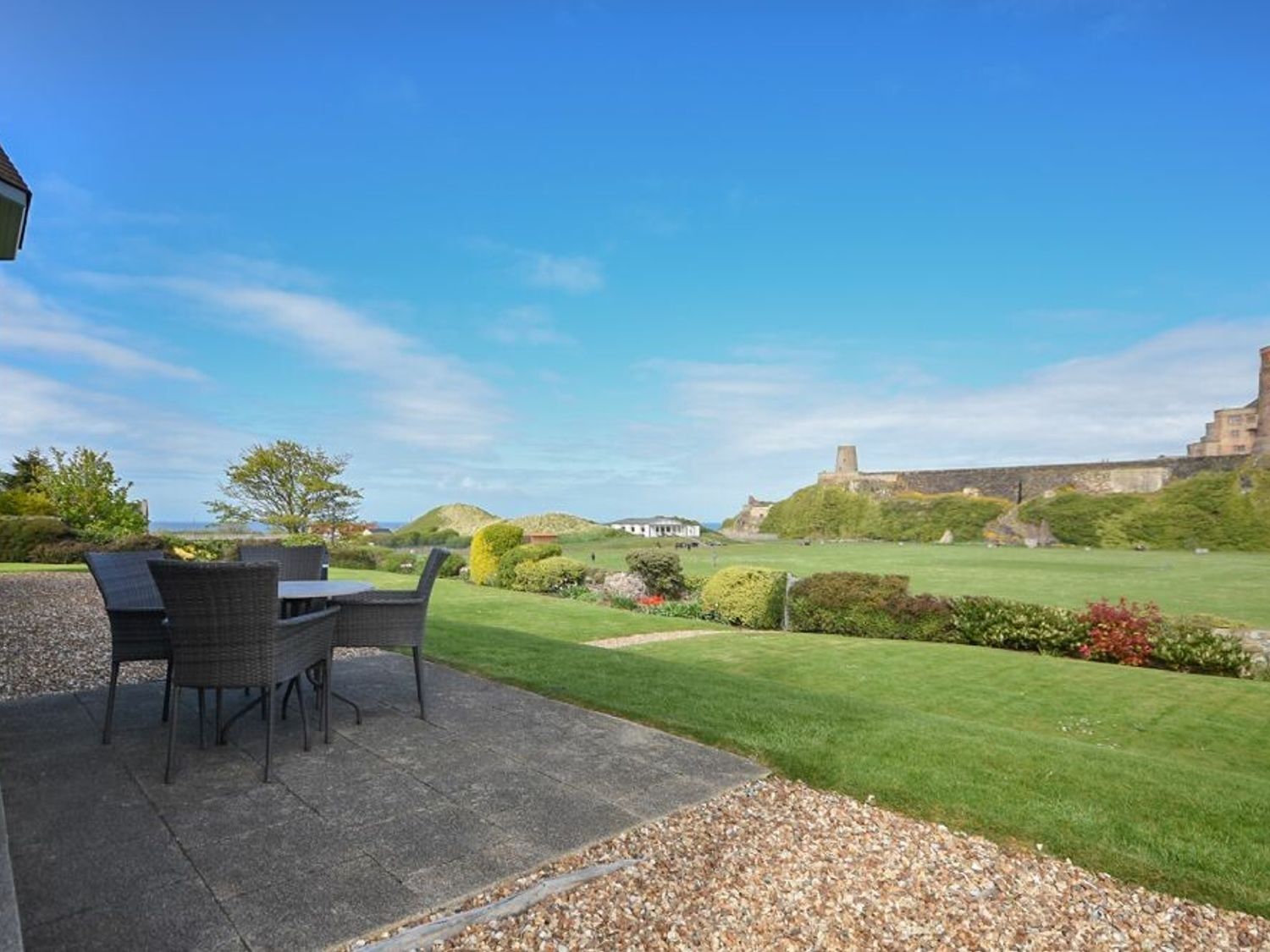 An outdoor patio with a table and chairs, a well-manicured lawn, and a castle in the background.
