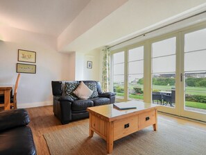 Ein Wohnzimmer mit einer Couch, einem Couchtisch und Blick durch große Glasfenster.