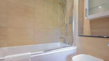 A modern bathroom with a bathtub, a toilet, and a glass shower enclosure.