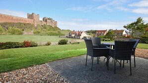Un patio con mobili da esterno, un prato verde e un castello sullo sfondo.