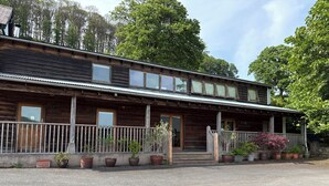 Ein Holzhaus mit Veranda, mehreren Fenstern und Blumentöpfen.