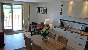 Een moderne keuken met een eethoek, met een houten tafel, rieten stoelen en een keukeneiland.