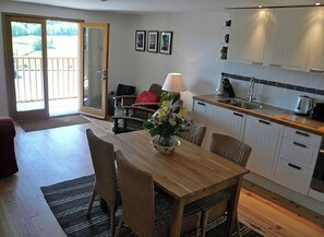 Una cocina moderna con comedor, que incluye una mesa de madera, sillas de mimbre y una isla de cocina.