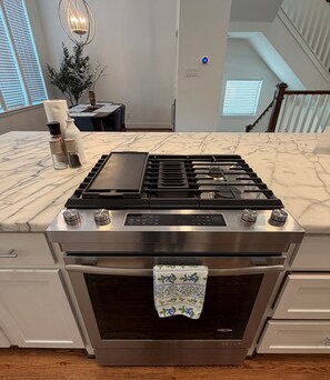 A kitchen with a stainless steel stove, oven, and marble countertop.