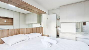 Ett modernt hotellrum med en säng, inbyggd garderob och en sänggavel i trä.
