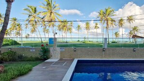 A swimming pool with a view of a beach and palm trees. - COSTE0114 - Inba Stella Residence (Salvador)