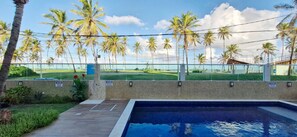 A swimming pool with a view of a beach and palm trees. - COSTE0114 - Inba Stella Residence (Salvador)