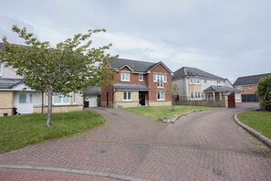 En villavej med huse, en asfalteret indkørsel og et træ.