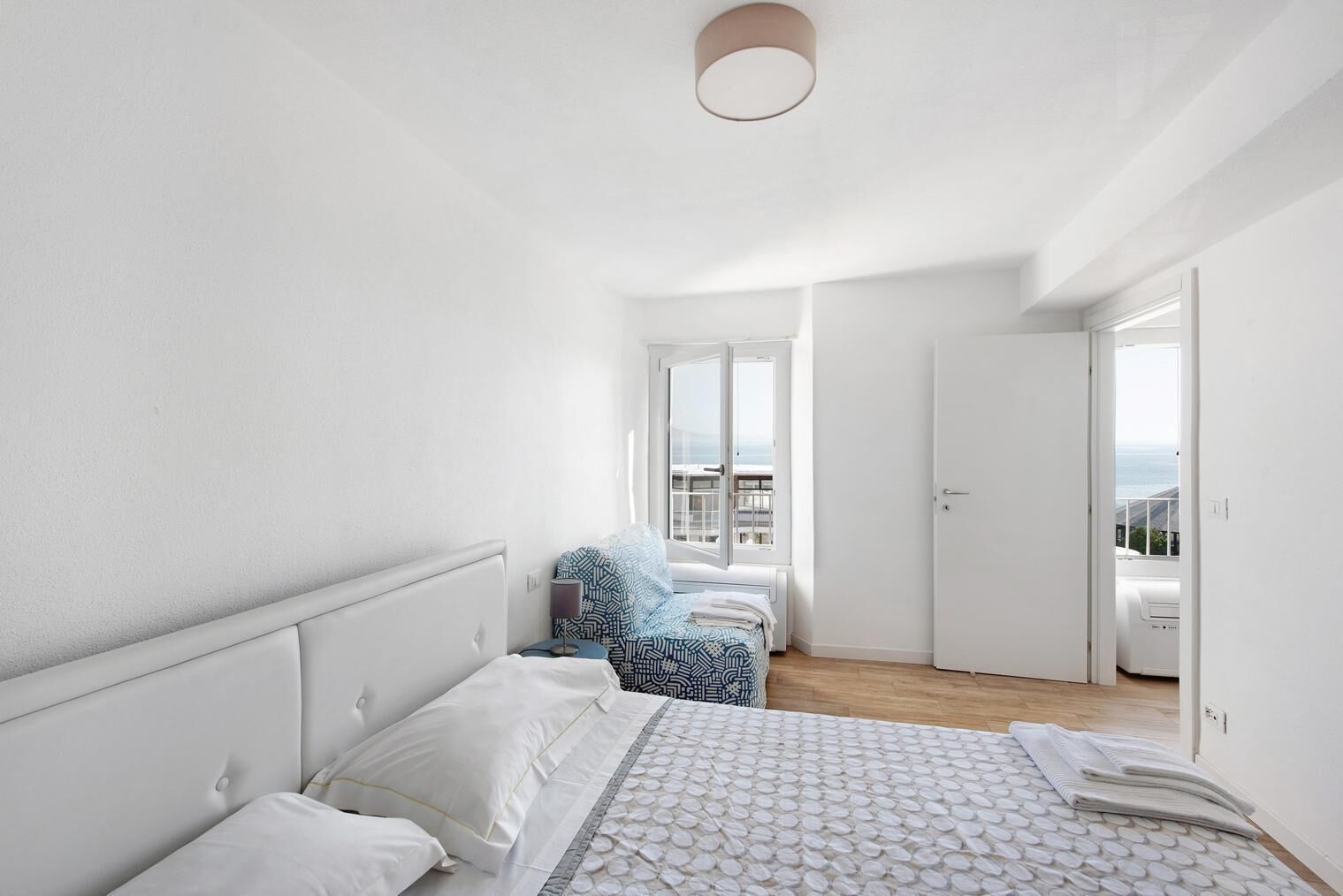 A bedroom with a bed, a chair, a window, and a door.