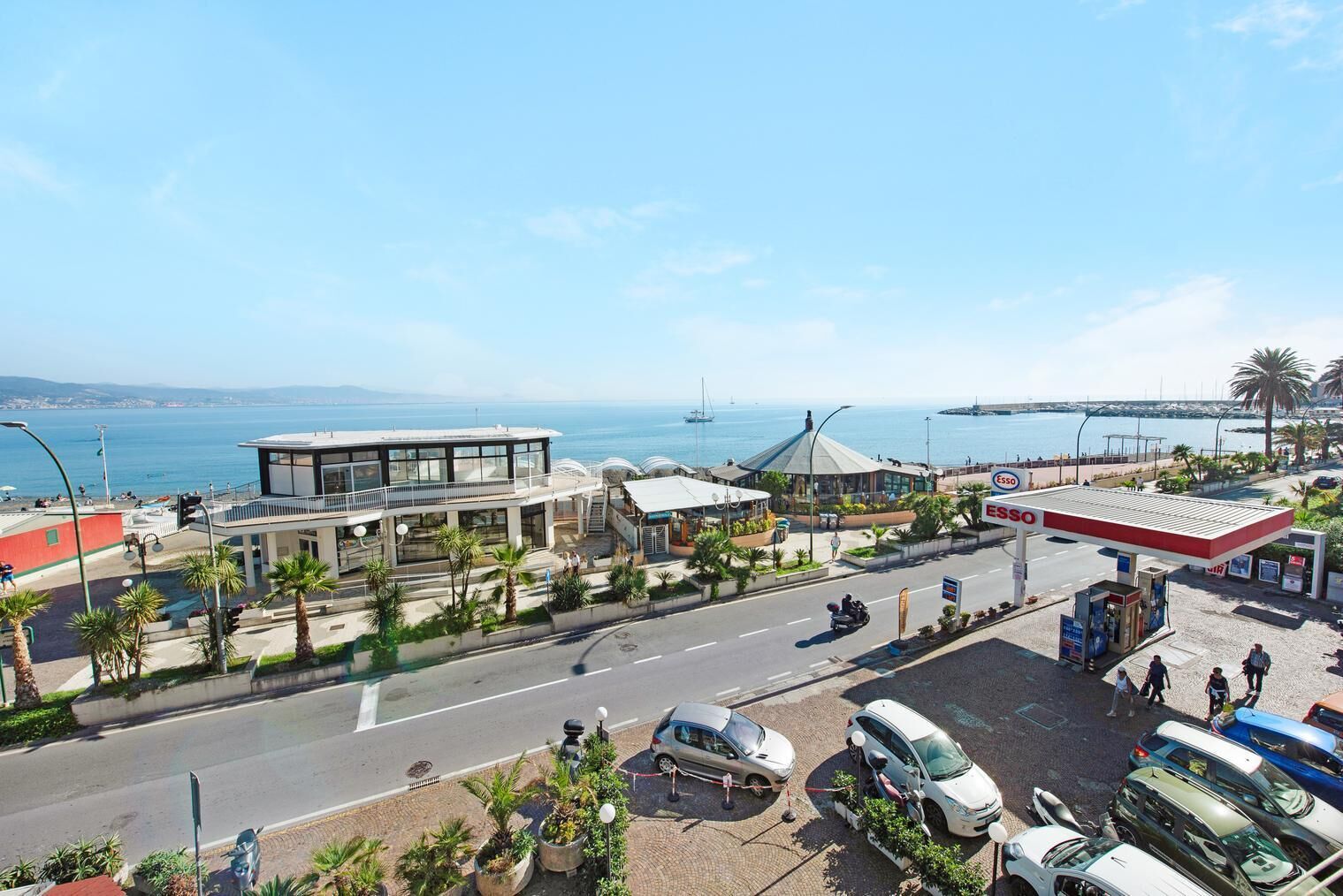 A coastal hotel with a modern design, a parking area, and a view of the sea.