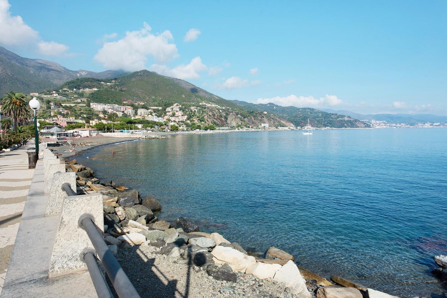 Un paseo marítimo con vista despejada al mar, un sendero de piedra y edificios al fondo.