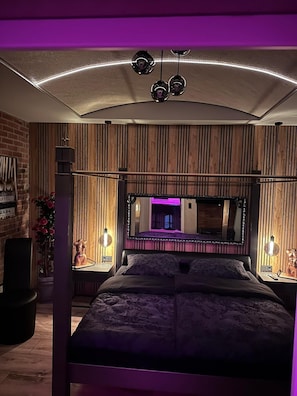 Ein Schlafzimmer mit einem großen Bett, einem Spiegel und Holzvertäfelung.