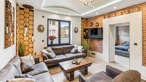 Ein modernes Wohnzimmer mit einer Sofagarnitur, einem Couchtisch und einem an der Ziegelwand befestigten Fernseher.